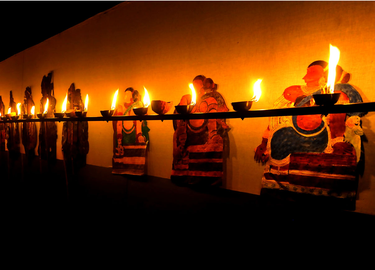 Decorated leather shadow puppets illuminated by a row of oil lamps